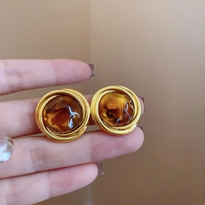 Macro detail of French vintage irregular gold earrings with amber resin inlay