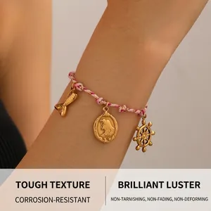 Gros plan du bracelet tressé rose avec breloques queue de sirène et gouvernail dorés