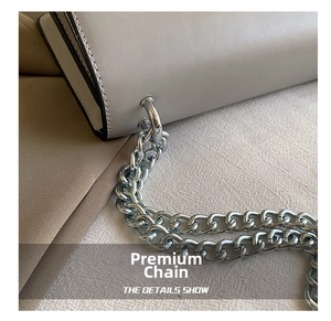 Detail of light gray leather shoulder bag with thick silver metal chain and fine stitching
