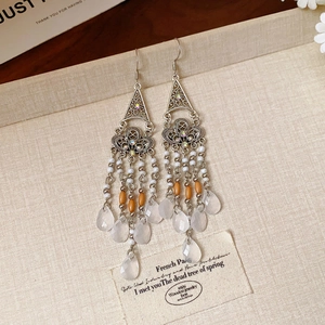 Close-up of vintage floral earrings with silver metal hollow carving and beaded tassels