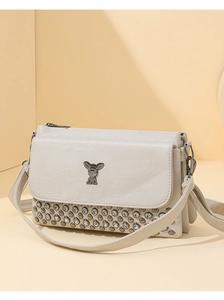 Close-up of beige crossbody bag with animal logo and rhinestone detailing on the bottom