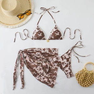 Detailed flat lay of a 3-piece floral bikini set with a sarong and golden pendant