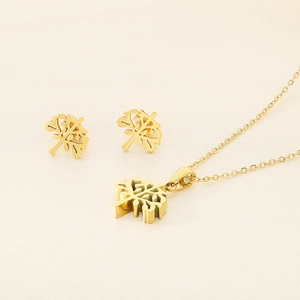 Detailed view of golden tree of life pendant necklace and stud earrings set on fabric