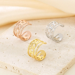 Detailed shot of twisted chain ear cuffs in gold, silver, and rose gold on marble