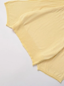 Gros plan d'un pull en tricot jaune clair avec texture fine et détails de bords côtelés