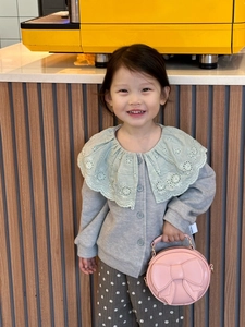 Pink round bow handbag styled with a grey cardigan and green collar on a child model