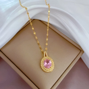 Détail d'un collier en titane doré avec pendentif en pierre rose dans un écrin