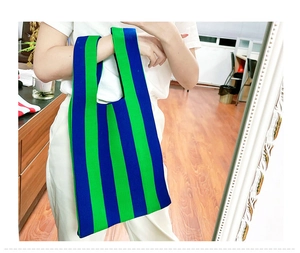 Close-up of blue and green vertical striped knit handbag with woven texture