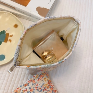 Floral makeup bag interior with cosmetics on a cozy home desk setup with books