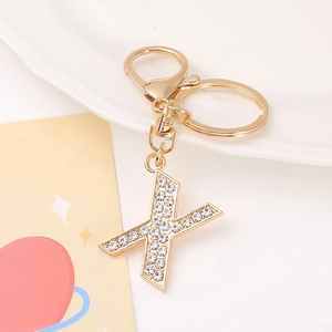 Detail view of a gold-tone letter X keychain featuring sparkling crystal rhinestones