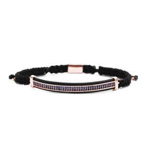 Detail of black braided rope bracelet with rose gold bar and micro-set blue zircon stones