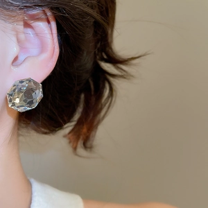 Close-up of clear faceted crystal stud earring on model showing elegant geometric design