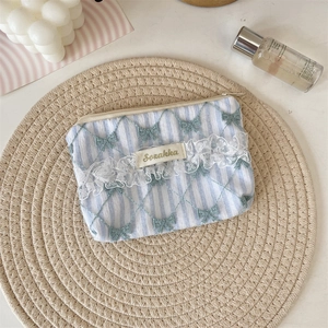 Detail of blue striped pouch with green bow embroidery and white lace trim edge