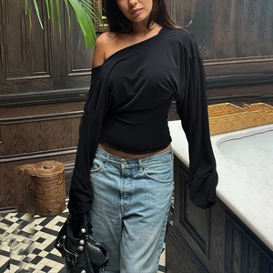 Detail of slim-fit black long-sleeve top featuring ruched fabric and off-shoulder V-neck