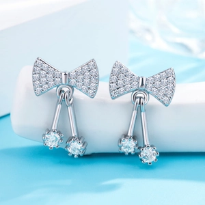 Close-up of silver bow and cherry earrings with sparkling white cubic zirconia stones