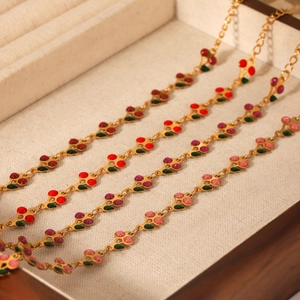 Detailed macro view of 18K gold-plated cherry bracelets with colorful enamel charms