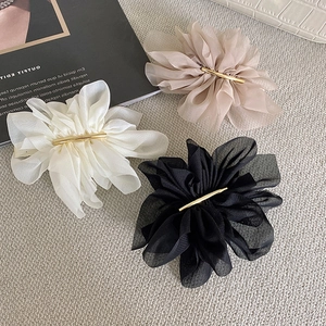 Detailed view of chiffon flower hair clips in beige, white, and black with gold barrettes