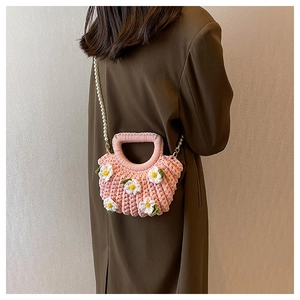 Detail of hand-woven pink shell bag with white daisies and elegant pearl strap