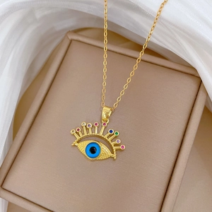 Golden evil eye necklace with colorful crystals on a soft beige jewelry box