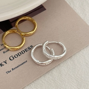 Detailed view of twisted gold and silver hoop earrings with spiral weave texture on card