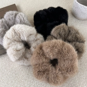 Five soft faux fur scrunchies in neutral colors displayed in a cozy lifestyle setting