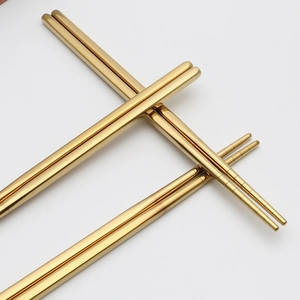 Pair of gold stainless steel chopsticks with spiral tips on a clean white background