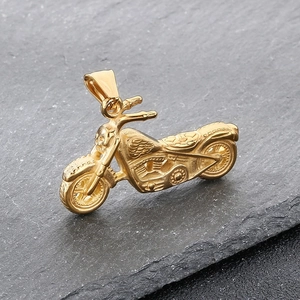Detail shot of a golden ghost rider motorcycle pendant with skull design on rocky texture