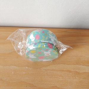 Detail of green Easter tin box with rabbit and egg patterns in clear plastic wrap