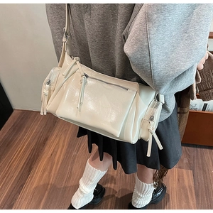 Détail du sac à bandoulière vintage crème avec fermetures éclair décoratives sur modèle