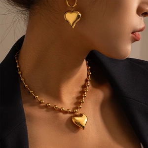 Detail of vintage gold puffy heart necklace and matching earrings set on a model