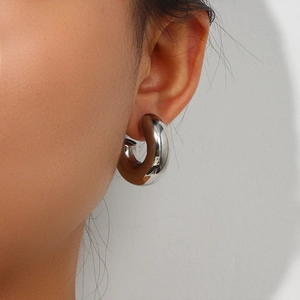 Close-up of stylish silver diamond-cut hoop earring worn on an ear for a modern look
