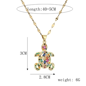 Detail of a golden turtle pendant with colorful zircon stones on a geometric chain