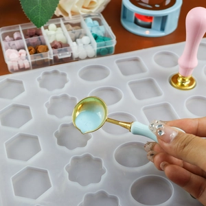 Detail of pouring wax with a metal spoon into a geometric silicone sealing wax mold