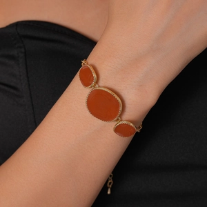 Gros plan d'un bracelet doré à maillons avec trois pierres ovales ambre sur poignet