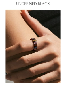 Macro detail of luxury black gold ring set with colorful rectangular gemstones on hand