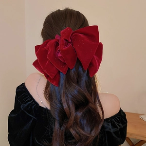 Macro shot of large red velvet layered bow hair clip on long dark curly hair