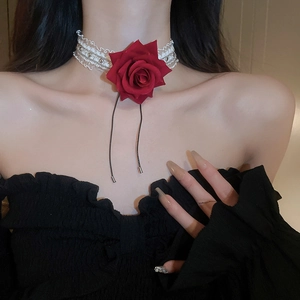 Detail of a white lace choker with a red rose flower and elegant black tassel ribbons