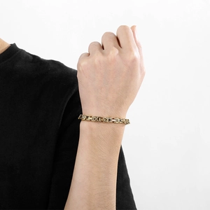 Dettaglio macro del bracciale bizantino in acciaio inossidabile dorato al polso