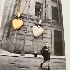 Detailed view of heart-shaped locket pendants in gold and silver on an artistic photo base