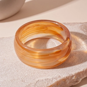 Detailed view of vintage amber acrylic bangle with elegant marble texture on a stone