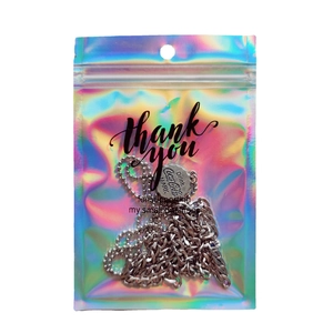 Holographic laser packaging bag with silver bottle cap pendant necklaces on white background