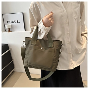 Detalle del bolso tote verde oliva con la correa de nailon ajustable y el clip metálico
