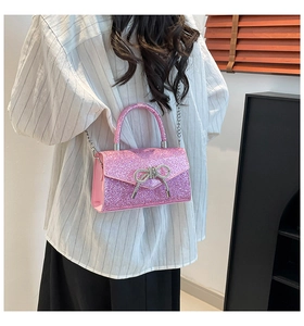 Pink sequin evening bag with silver bow shown carried by a model in casual attire