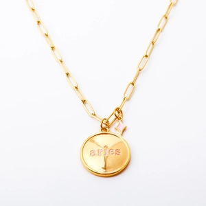 Collana ovale Ariete dorata con scritte rosa su catena a graffetta su sfondo bianco