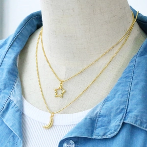 Detail of double-layer gold necklace with colorful star and crescent moon pendants