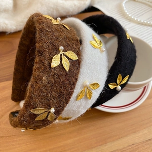 Close-up of velvet leaf headbands with pearls and gold metal accents in three colors