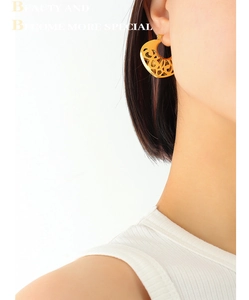 Gros plan de boucles d'oreilles cœur dorées avec motifs floraux vintage sur un mannequin