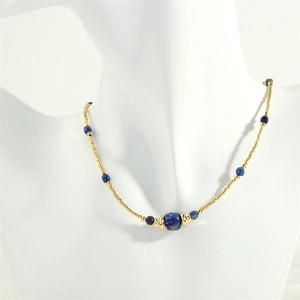 Detailed shot of Amazonite necklace with golden beads and square blue stone on model
