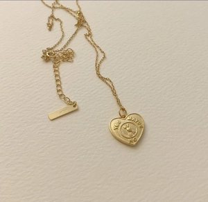 Macro detail of gold S925 silver heart necklace with Yes Maybe No engraving and chain