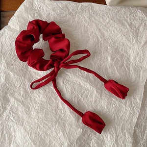 Detail of wine red satin scrunchie with long ribbons and tulip flower bud pendants